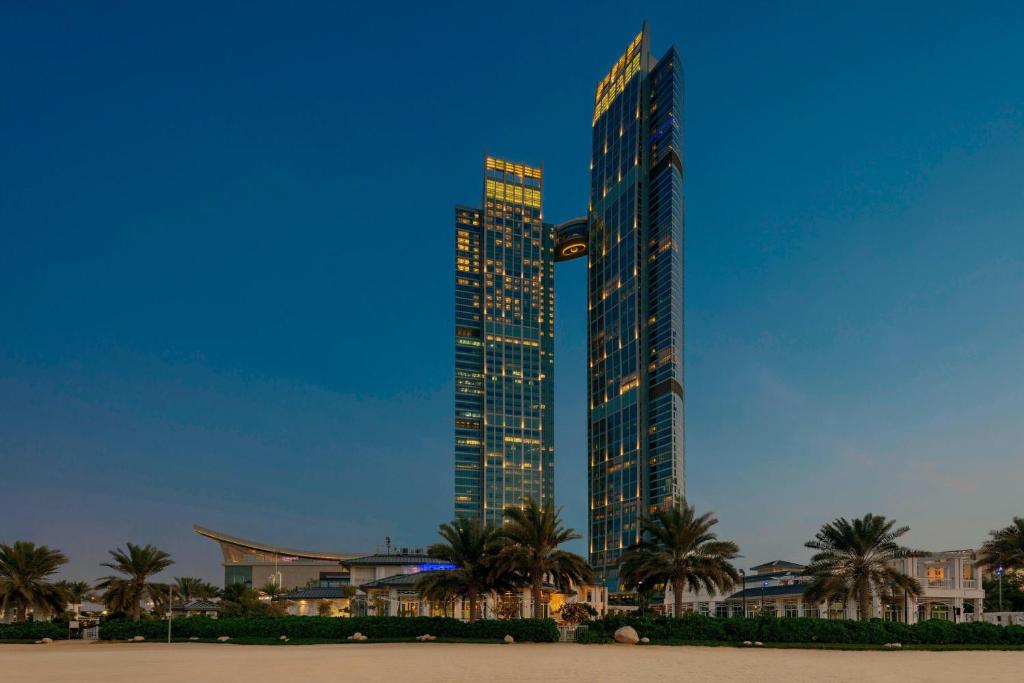 un grand bâtiment avec des palmiers devant lui dans l'établissement The St. Regis Abu Dhabi, à Abu Dhabi