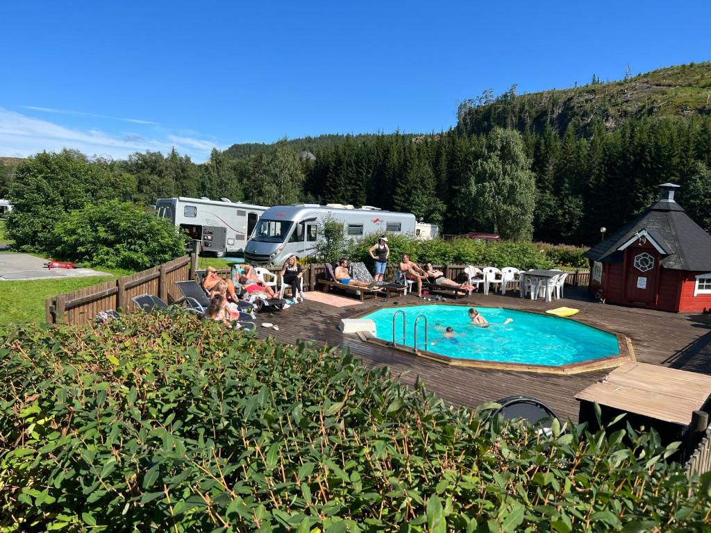 een groep mensen die rond een zwembad in een camper park zitten bij Gullvåg Camping Nyberg in Soknedal