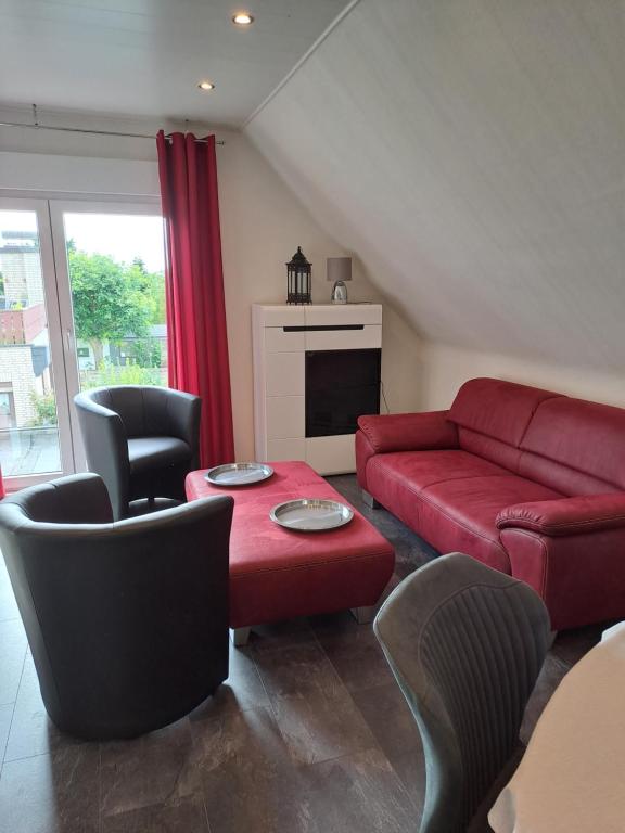 sala de estar con sofá rojo y sillas en An den Eichen en Neustadt am Rübenberge
