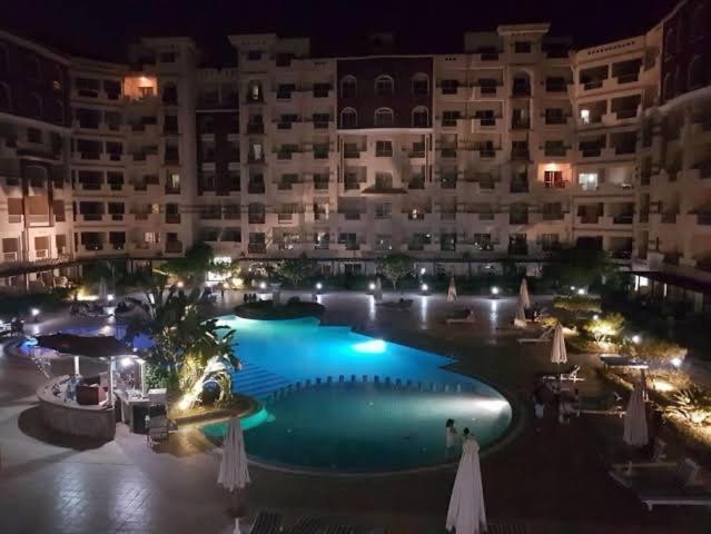 a large swimming pool in front of a building at night at Florence khamsin - dream house in Hurghada