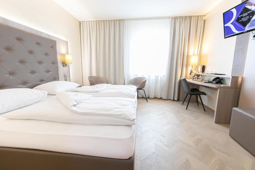 um quarto de hotel com duas camas e uma secretária em Das Reinisch Hotel & Restaurant em Schwechat