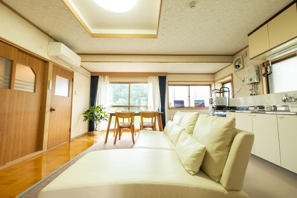 ein Wohnzimmer mit einem weißen Sofa und einer Küche in der Unterkunft Stay in Yamabe in Furano