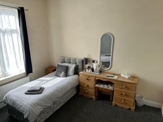 a bedroom with a bed and a dresser with a mirror at The Grosvenor Free house in Scunthorpe