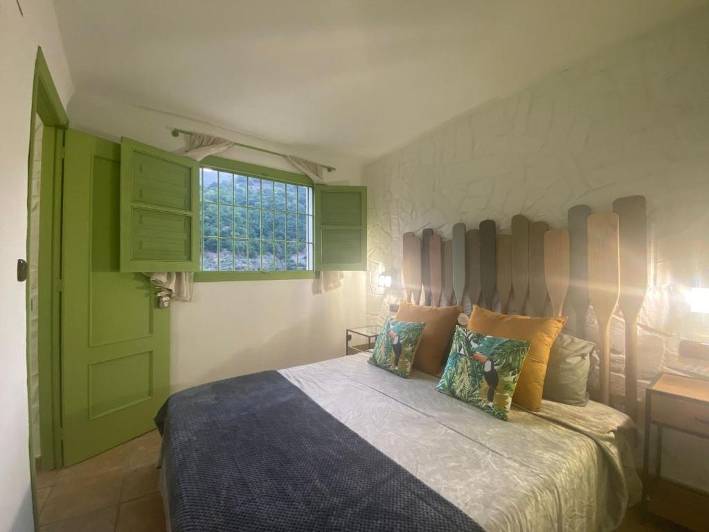 a bedroom with a bed with green doors and a window at La Lozana in Jete