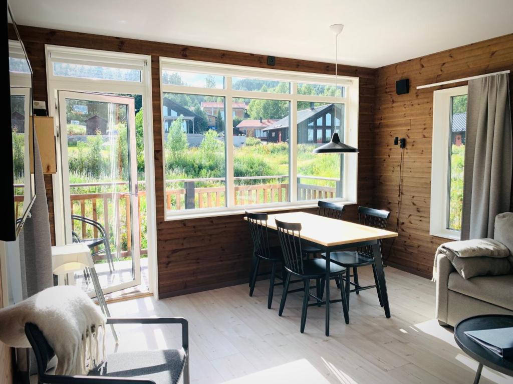 a dining room with a table and chairs and windows at Fin lägenhet med bastu i Järvsö! in Järvsö