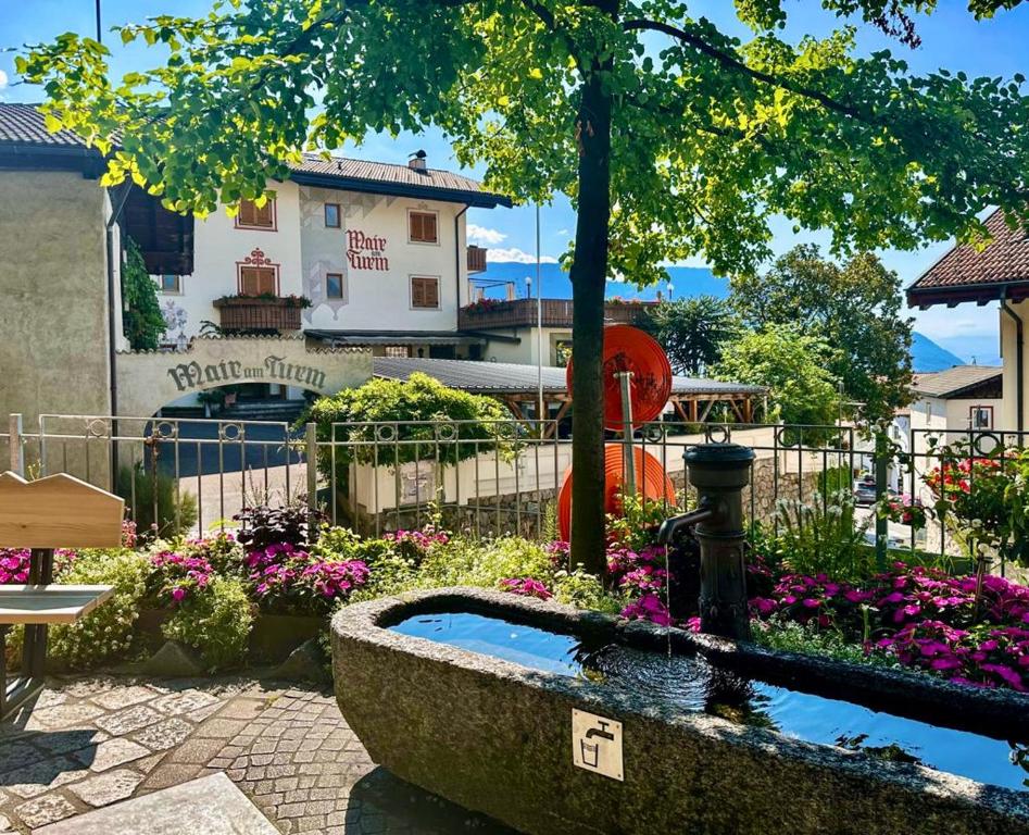 un jardín con una fuente y flores frente a un edificio en B&B Hotel Mair am Turm en Tirolo