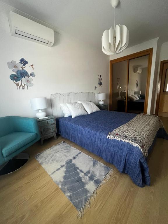 a bedroom with a blue bed and a blue couch at Cozy Apartment in Santa Luzia