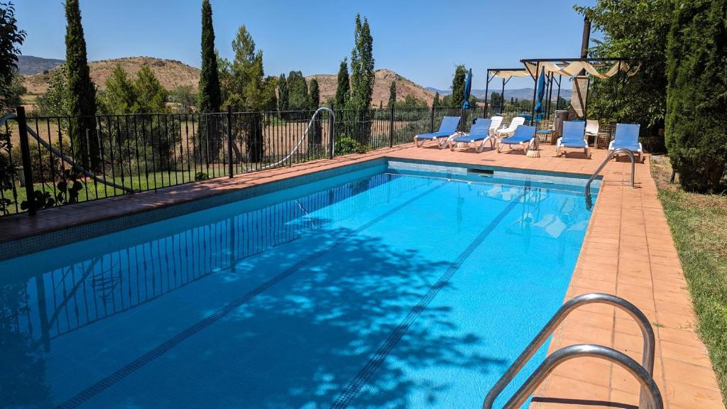 a swimming pool with chairs and a swing at Casas Rurales Los Cortijos in Alcaraz