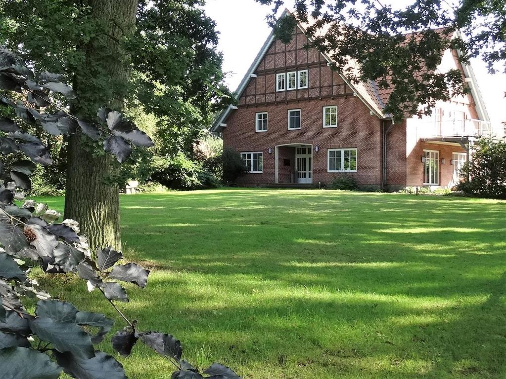 ein großes Backsteingebäude mit einem Baum im Hof in der Unterkunft Landhaus Eichengarten in Soltau