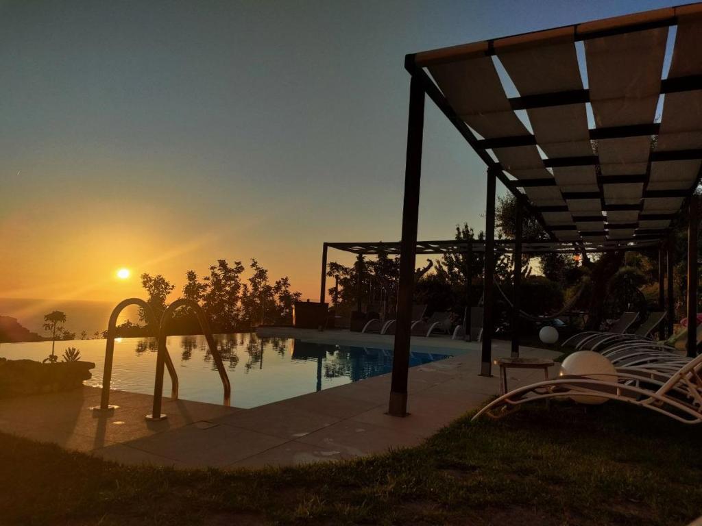 a swimming pool with a sunset in the background at Il Podere dell'Angelo Old Country House in Belvedere Marittimo