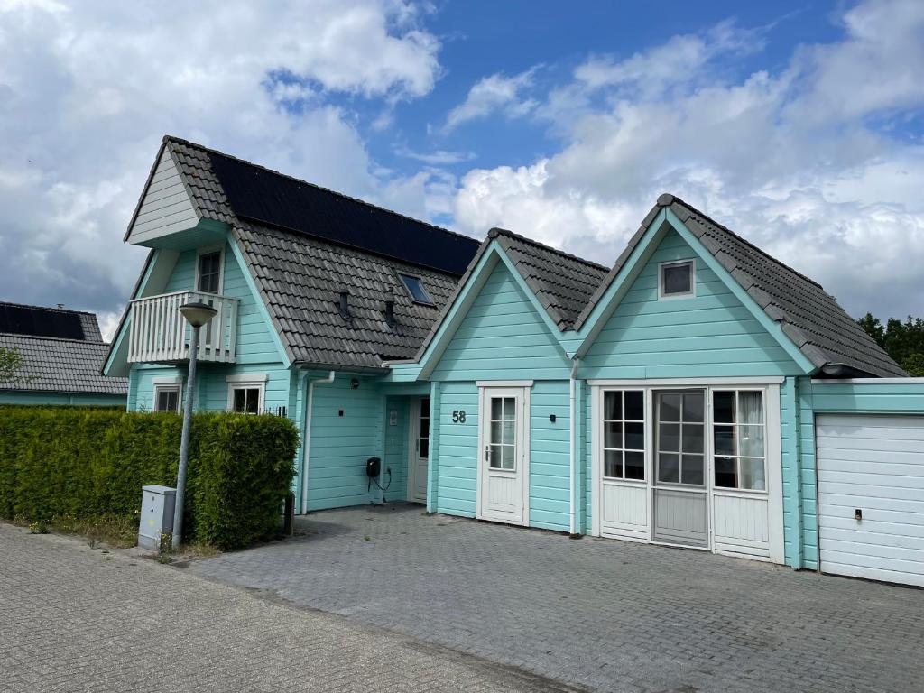una casa azul y blanca con garaje en Vrijstaande luxe Finse blokhut 2-6 of 2-8 pers, en Kropswolde