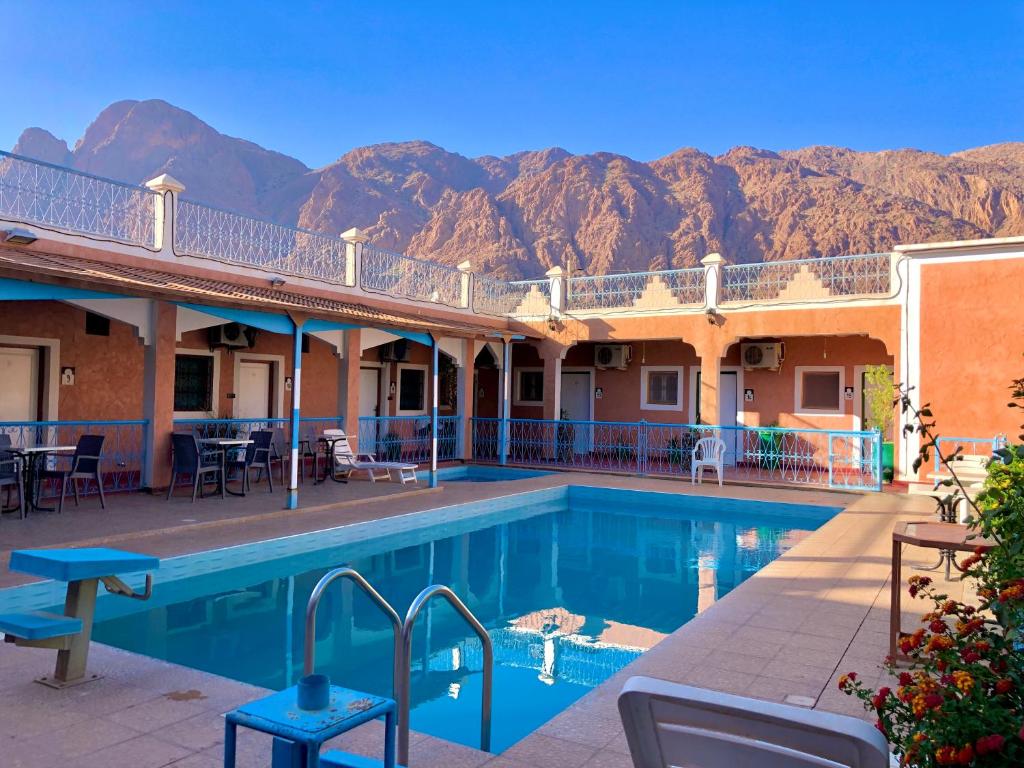 a hotel with a pool and mountains in the background at Hotel L'Arganier d'Ammelne in Tafraout