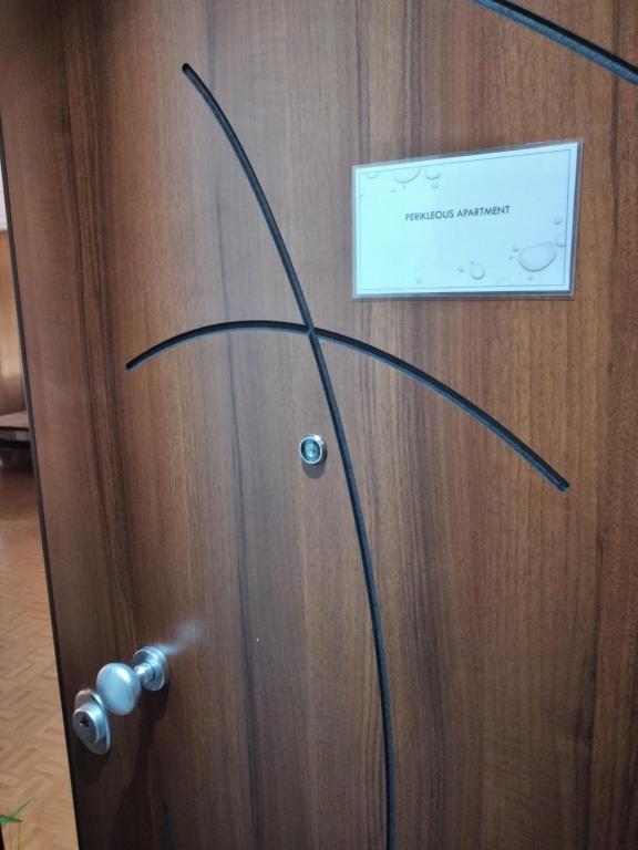Una puerta de madera con un cartel en Perikleous Apartment, en Atenas