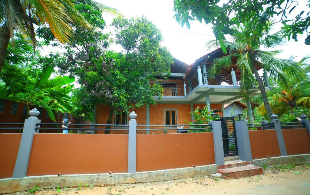 a house with an orange fence and palm trees at Ammu villa in Point Pedro