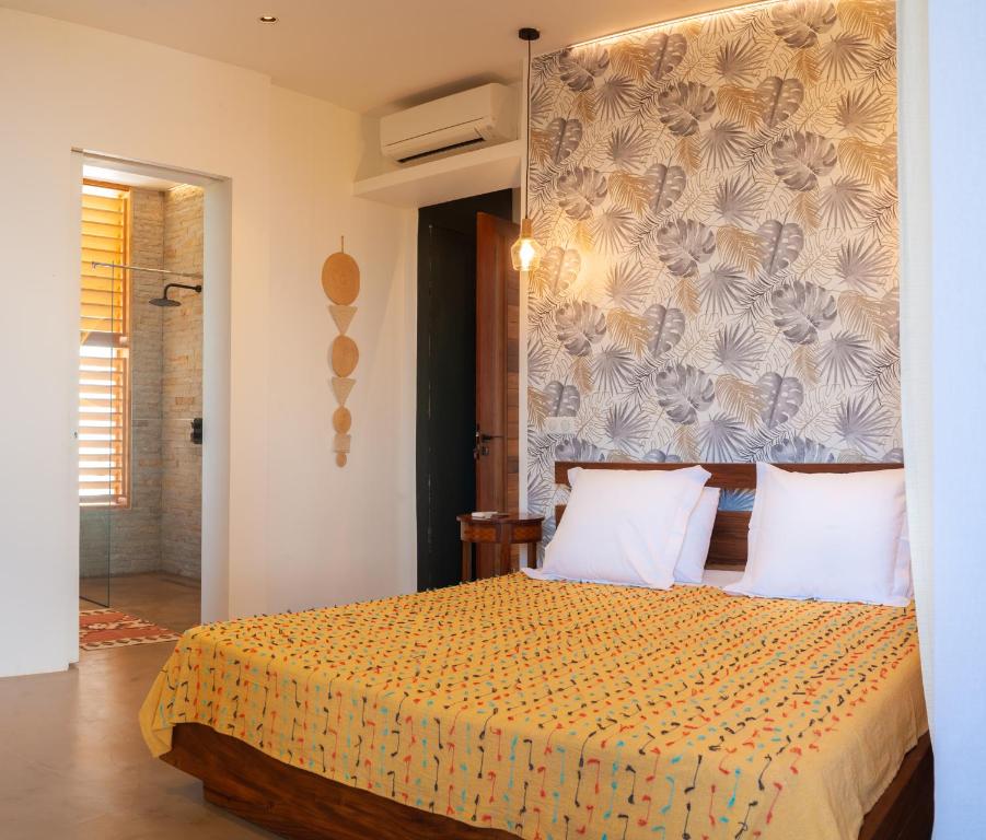 a bedroom with a large bed with a wall at PASSOT HILLS in Nosy Be