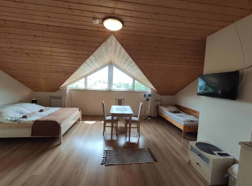 een slaapkamer met 2 bedden, een tafel en een raam bij Widok apartamenty domki pokoje 725 -258 -751 in Polańczyk