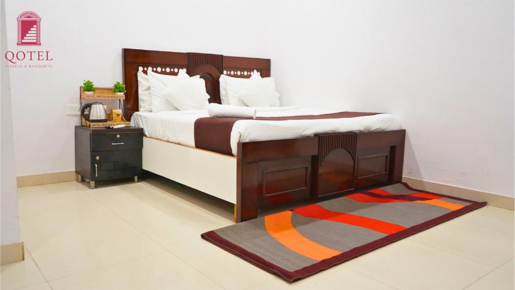 a bedroom with a bed with a wooden frame and a rug at Qotel Hotel Peeragarhi-Near Peeragarhi metro Station,Couple Friendly in New Delhi
