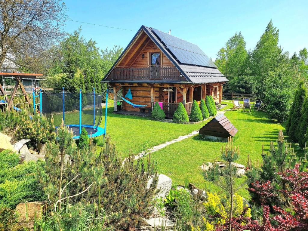 a wooden house with a playground in the yard at Hyta na Bani- domek Rabka Zdrój in Skawa