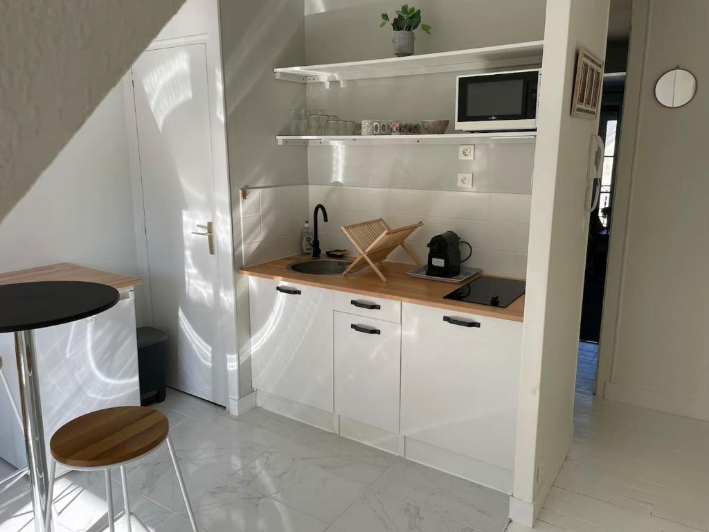 a kitchen with white cabinets and a sink and a microwave at *Le Baudin : T2 cosy vue dégagée in Limoges