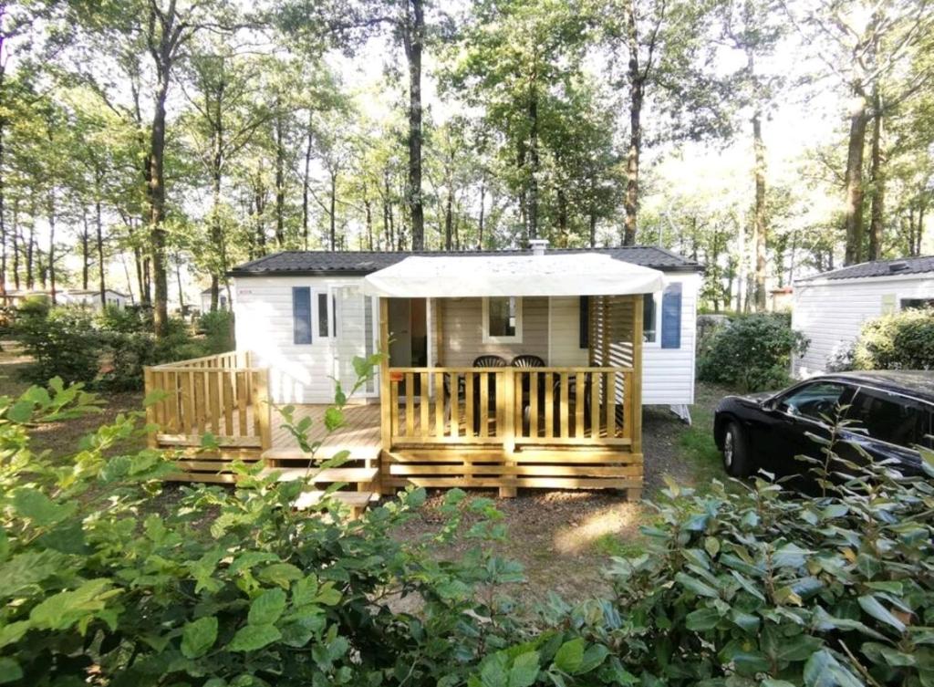 una pequeña casa blanca pequeña con porche en Mobil Home 6 personnes 3 chambres à 25 MIN Puy duFou en La Boissière-de-Montaigu