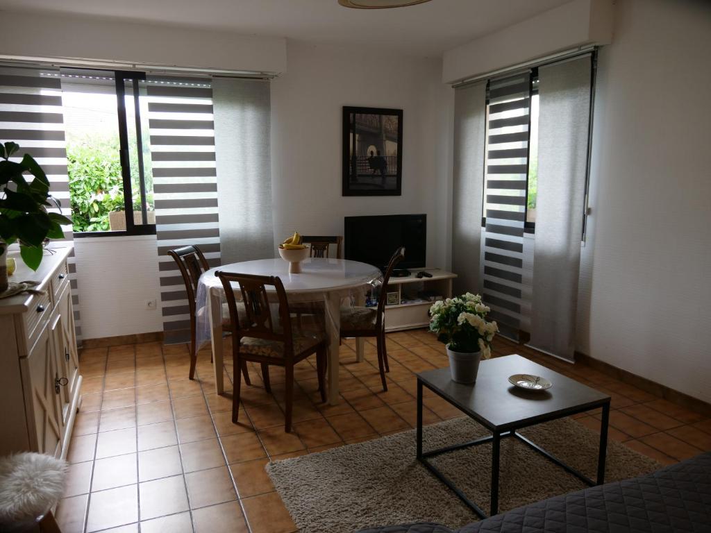 a living room with a table and chairs and a television at Chez Martine Appartement tout confort entièrement indépendant in Pau