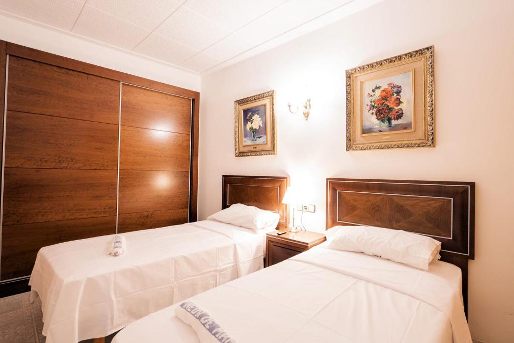 L'Hostalet GuestHouse في باينيدا دي مار: سريرين في غرفة الفندق ذات شراشف بيضاء