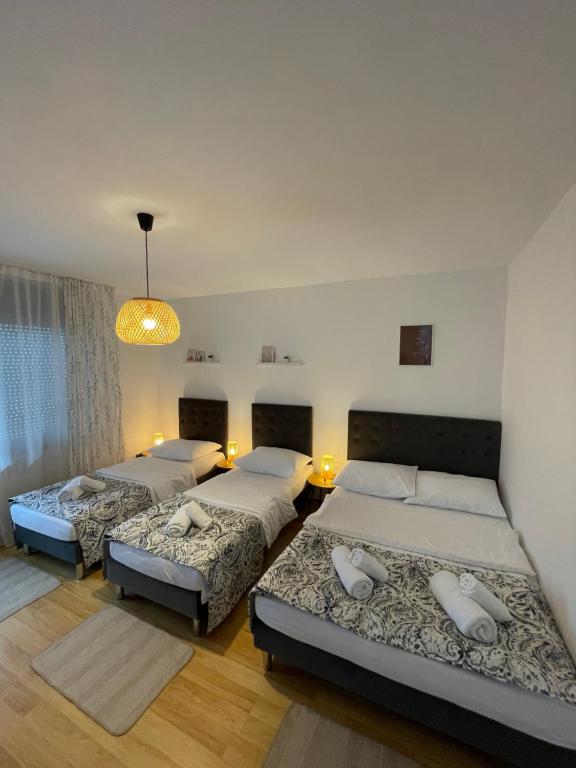 a bedroom with three beds and a chandelier at Comodo apartman Vinkovci in Vinkovci