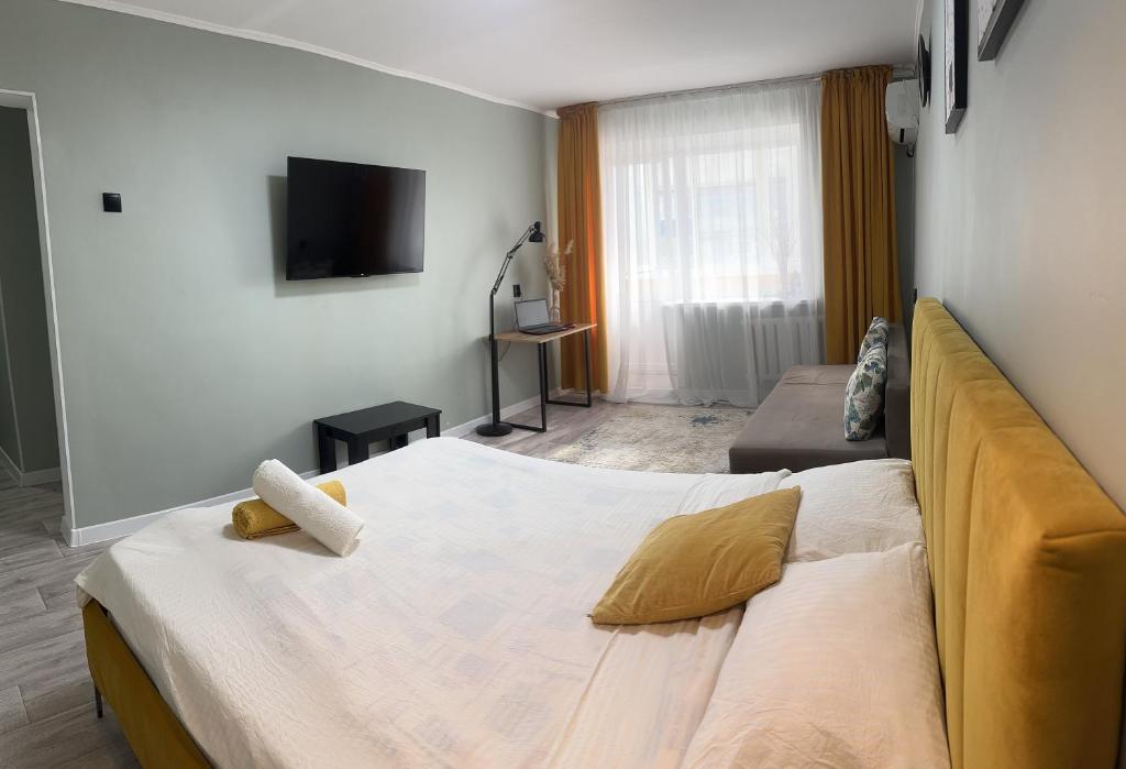 a bedroom with a large bed and a television at Новый центр с электронным замком! in Uralʼsk