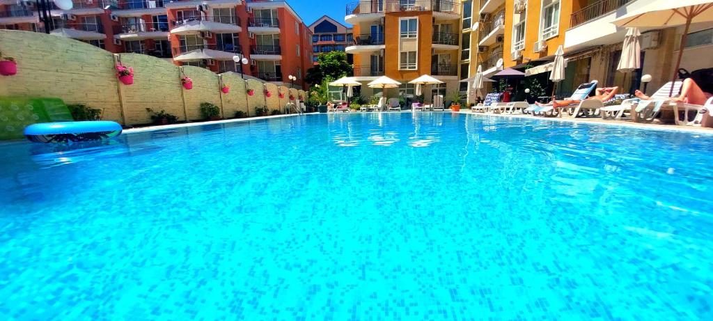 a large blue swimming pool with chairs and buildings at Blue Marine - Menada Apartments in Sunny Beach