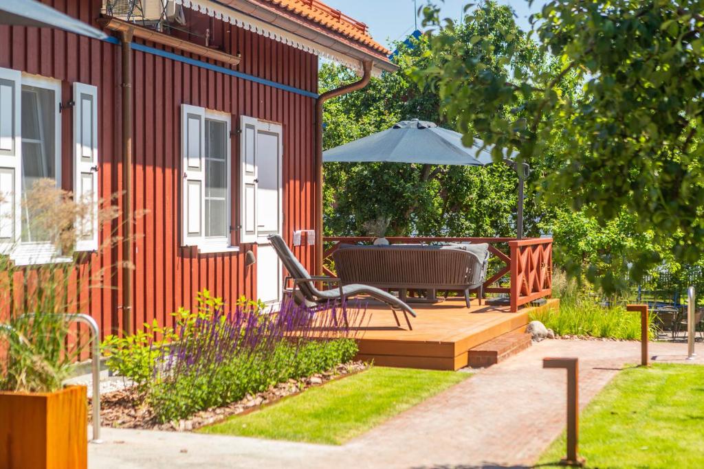 a wooden deck with an umbrella next to a house at Nauji apartamentai! Pamario 14 in Nida