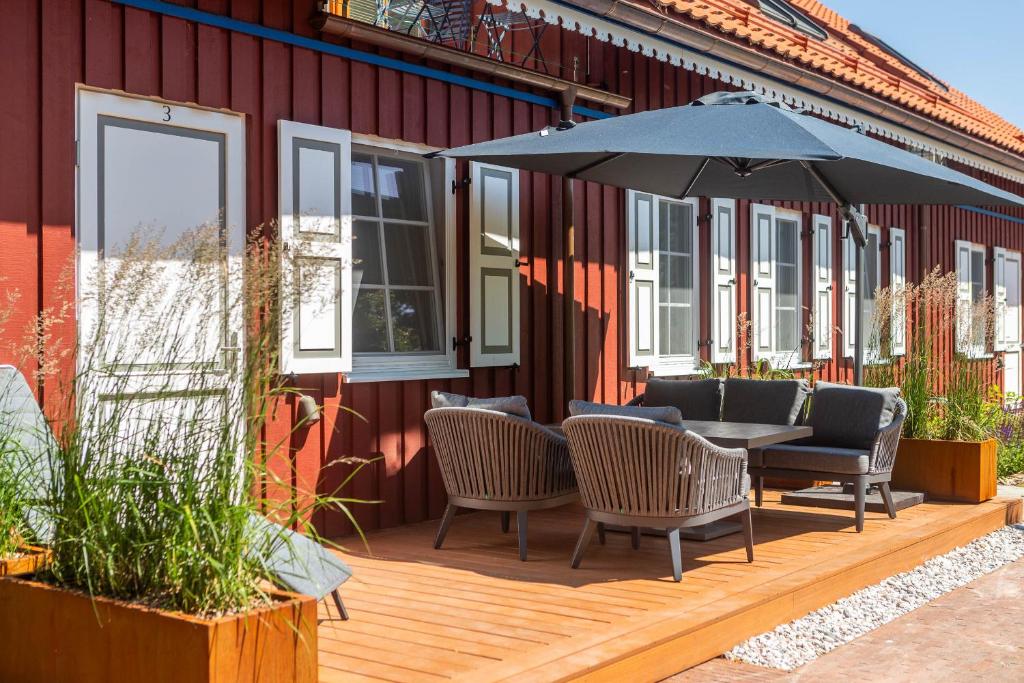 a wooden deck with a table and chairs and an umbrella at Nauji apartamentai! Pamario 14 in Nida