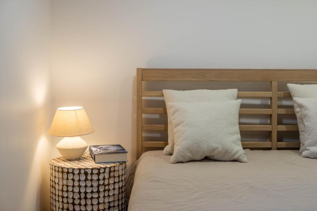 a bedroom with a bed with a lamp on a table at Nauji apartamentai! Pamario 14 in Nida
