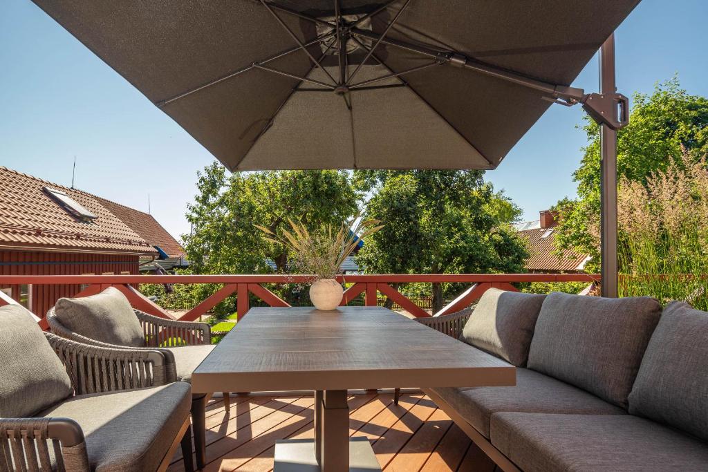 a wooden table with chairs and an umbrella on a deck at Nauji apartamentai! Pamario 14 in Nida