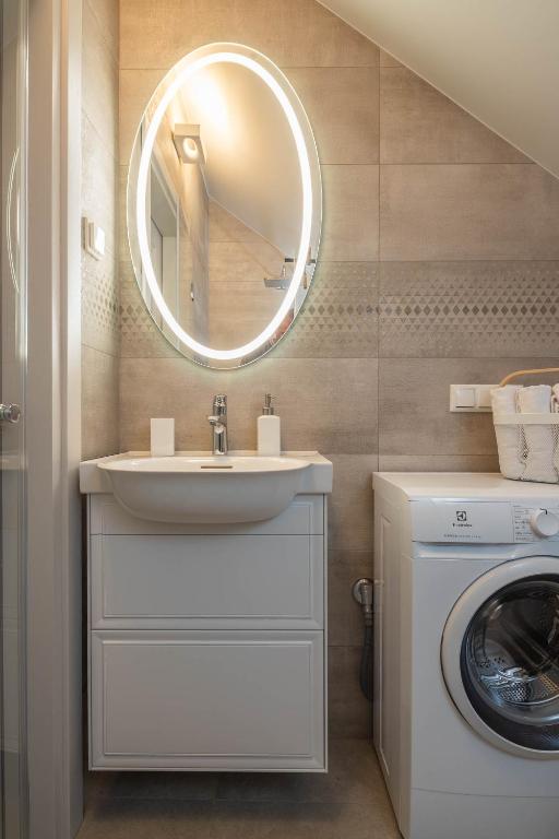 a bathroom with a sink and a washing machine at Nauji apartamentai! Pamario 14 in Nida
