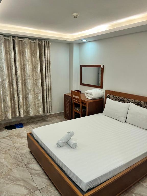 Schlafzimmer mit einem Bett, einem Schreibtisch und einem Spiegel in der Unterkunft Hotel Thanh Ngọc in Ho-Chi-Minh-Stadt