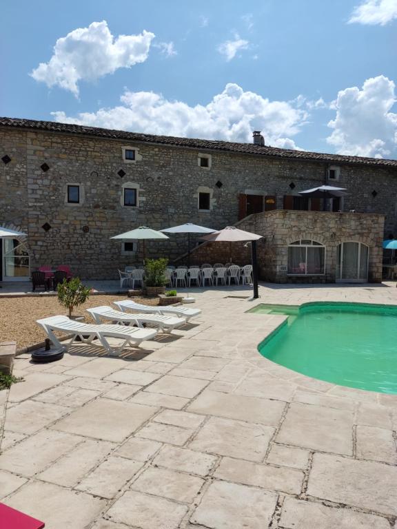 un complexe avec une piscine, des chaises et un bâtiment dans l'établissement Les cigales gîte cigalou, à Grospierres