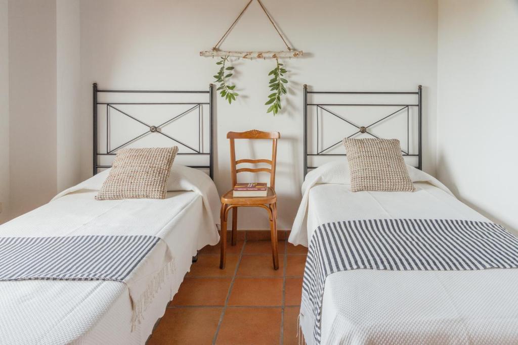 - 2 lits dans une chambre avec une chaise dans l'établissement Casa Rural en Candeleda con piscina y un maravilloso jardín, à Candeleda