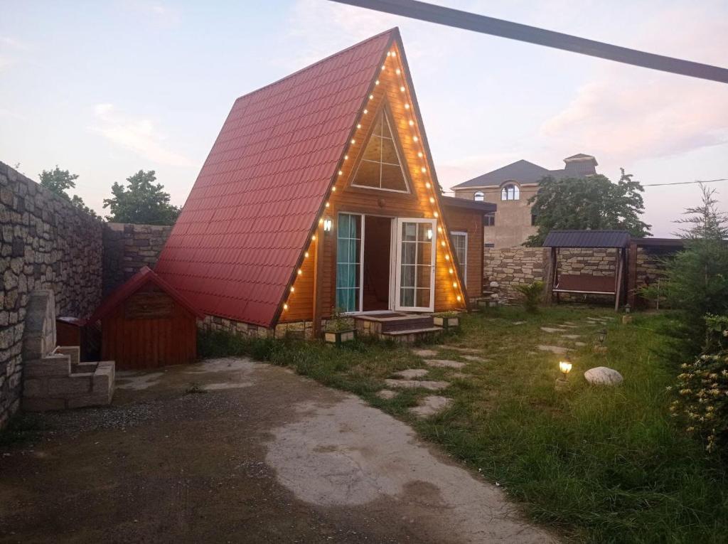 una pequeña casa con un techo rojo con luces encendidas en Quba A frame en Amsar