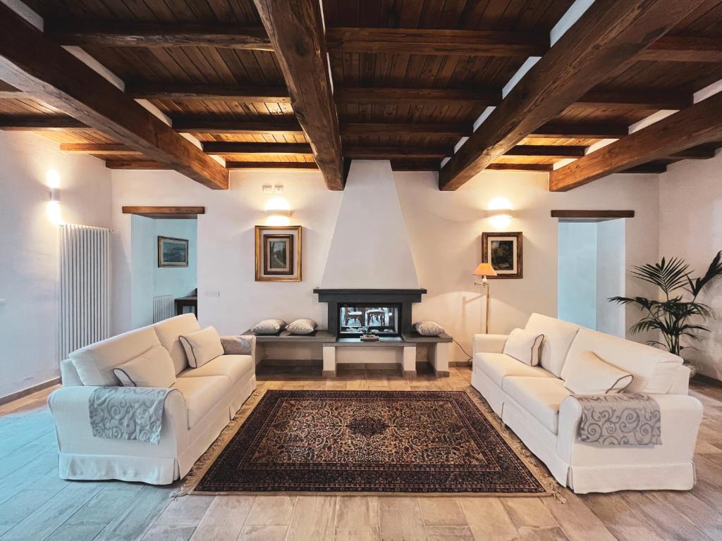 a living room with two white couches and a fireplace at L'Antico Asilo in Stazzema