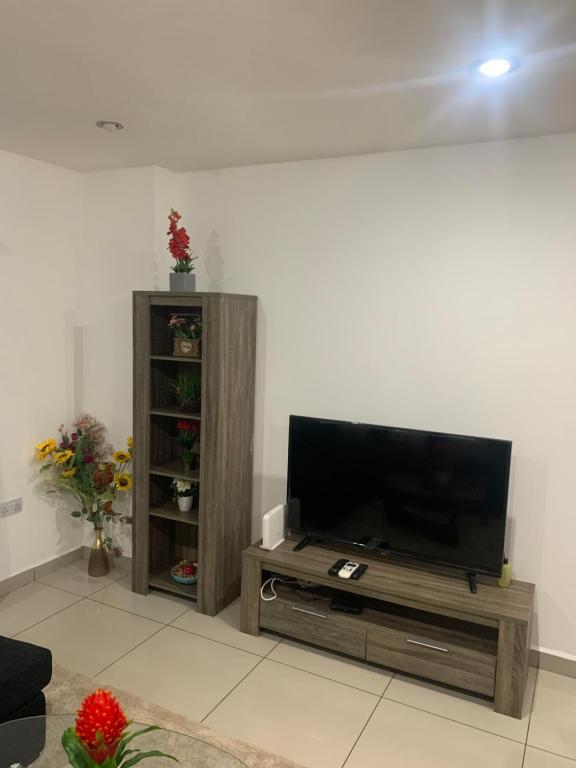 uma sala de estar com uma televisão de ecrã plano num centro de entretenimento em madeira em City Views Apartment em Bawaleshi