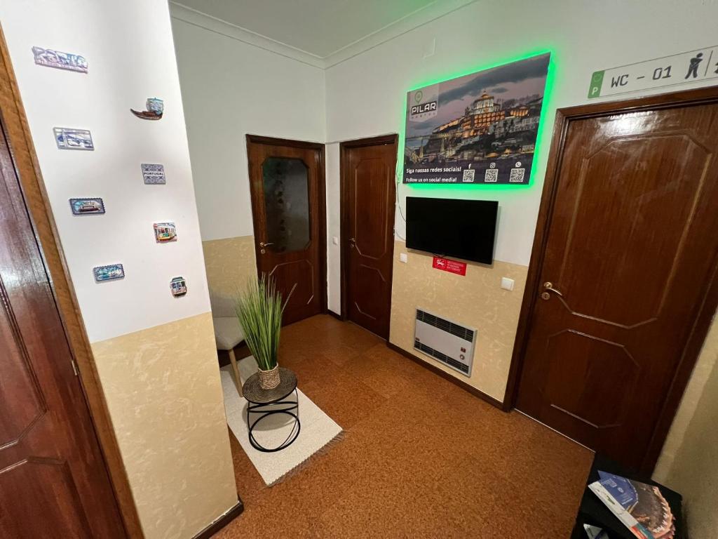 a hallway with two doors and a television and a plant at Pilar Hostel - Rua de Santa Catarina - Porto in Porto