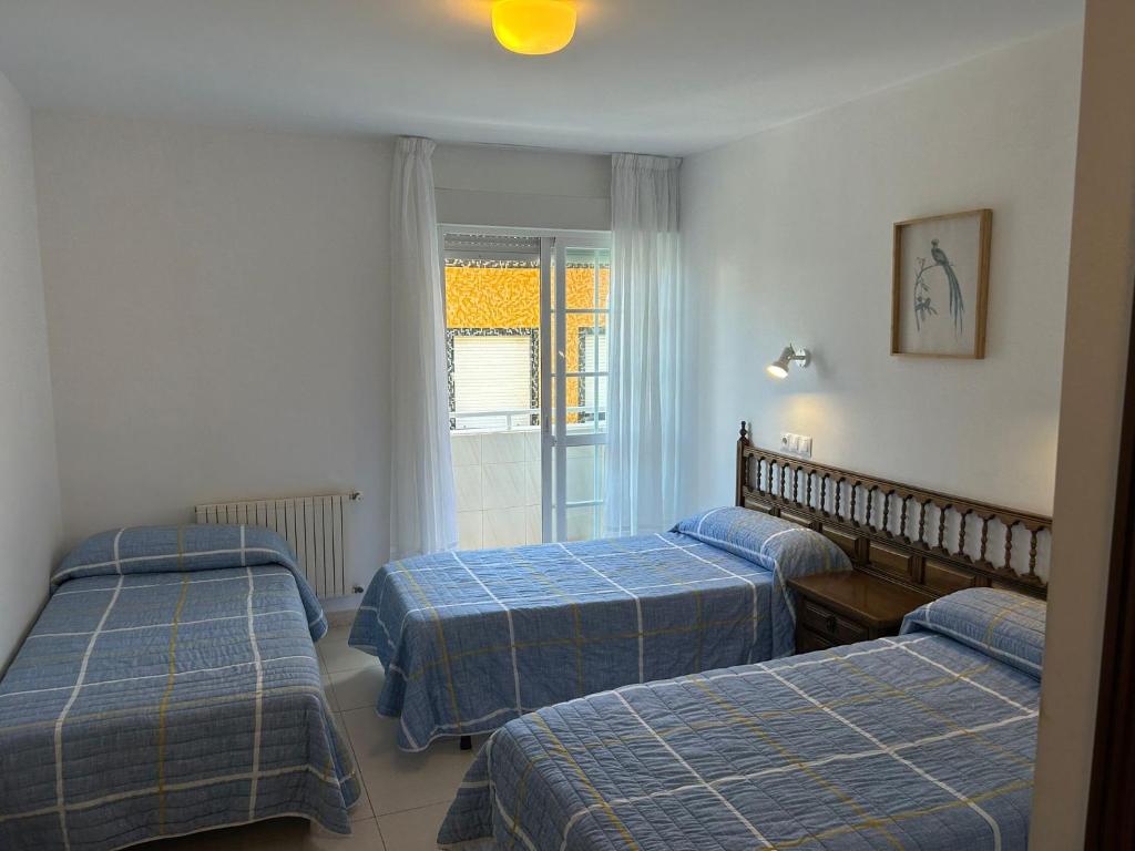 a room with three beds and a window at Pensión Rey in Isla de Arosa