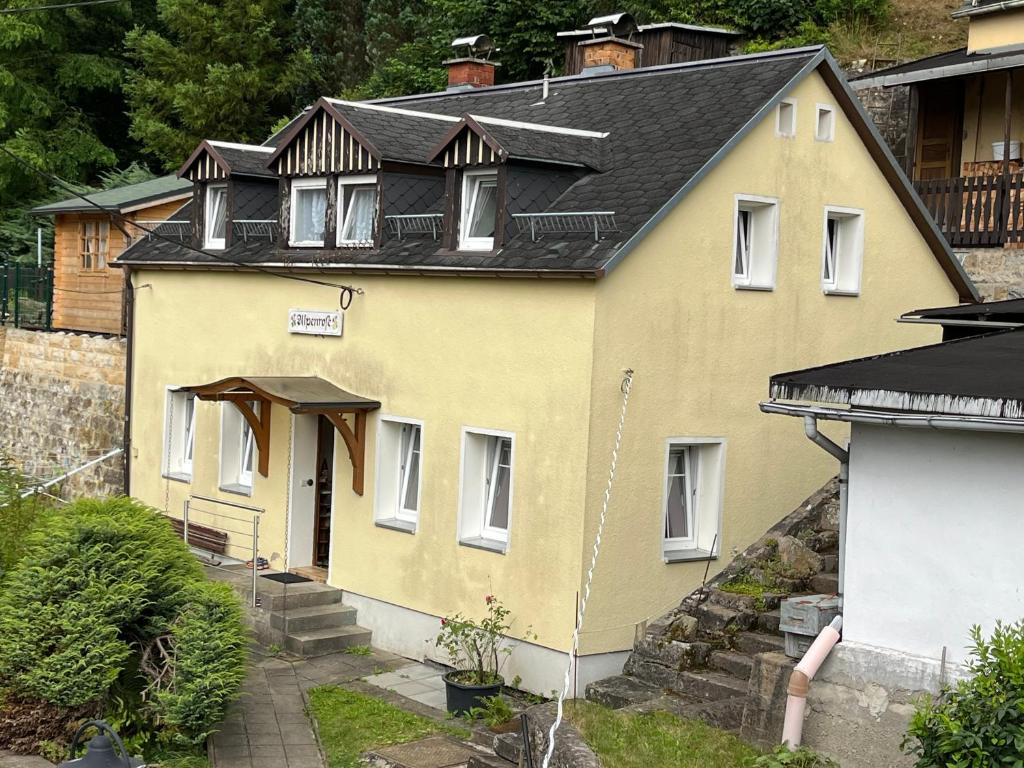 una casa amarilla con techo negro en Pension Alpenrose, en Bad Schandau