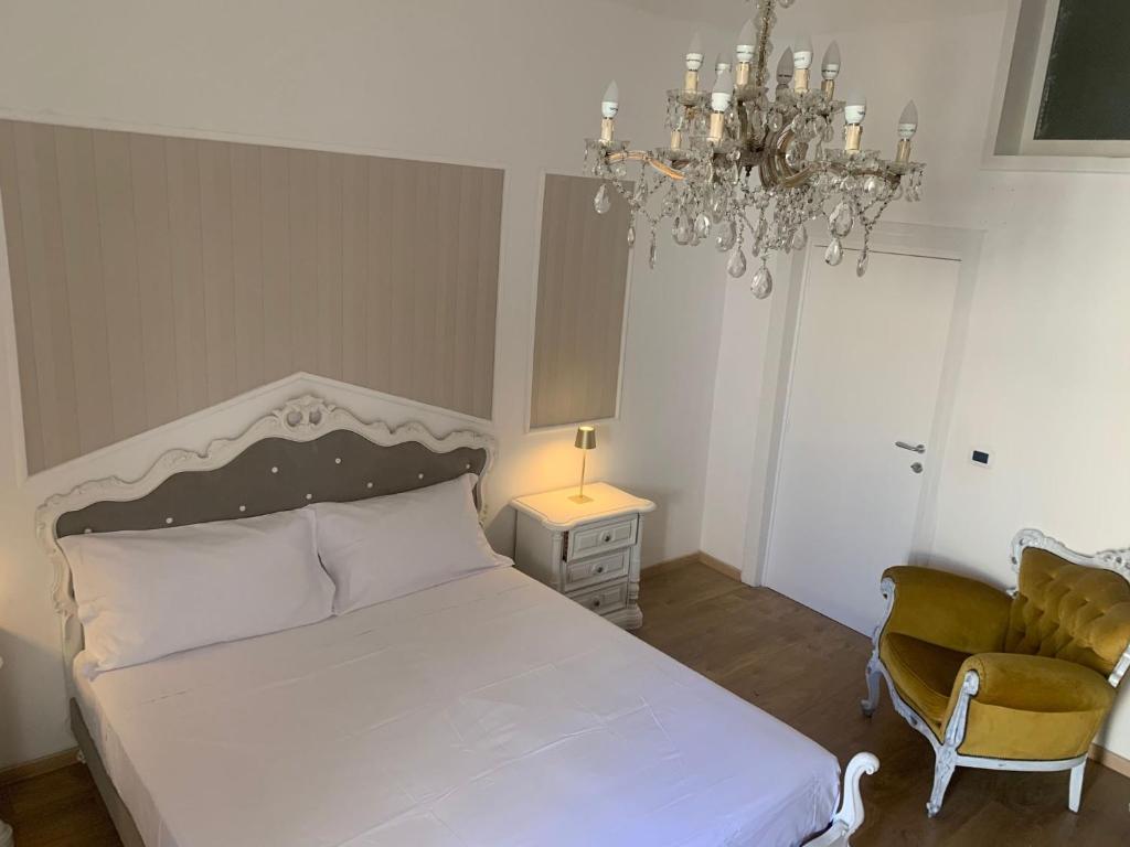 um quarto com uma cama, uma cadeira e um lustre em Geometric Hermes Bianca em Palo del Colle