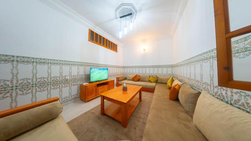 un soggiorno con divano e TV di Abdessamad Appartement 2 a Essaouira