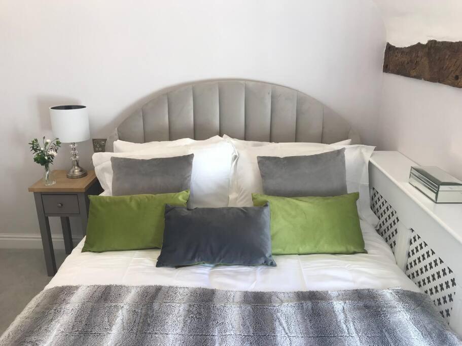a bed with green and white pillows on it at Boutique style cottage Bridgnorth in Bridgnorth