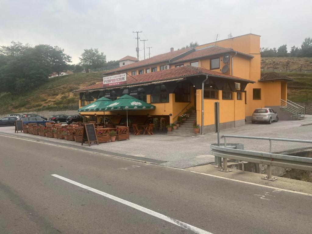 a building with tables and umbrellas on the side of a road at Motel Rudnicki Konak in Topola
