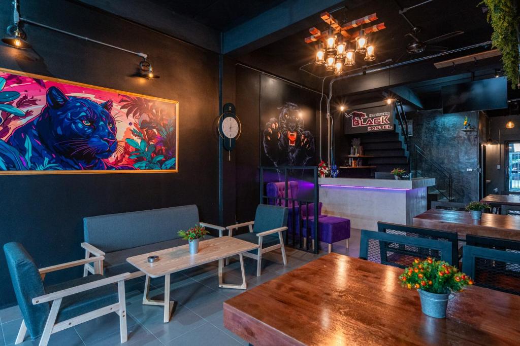 a restaurant with tables and chairs and a painting on the wall at Black Panther Hostel in Phuket