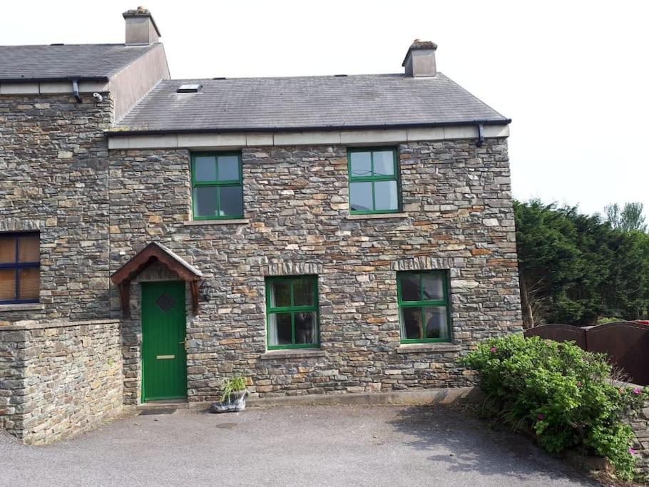 Casa de piedra con puerta verde y ventanas en The Cobbler Rosscarbery Holiday Cottage, en Rosscarbery