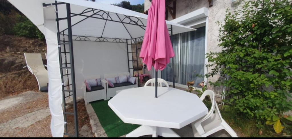 a patio with a white table and an umbrella at Bas de maison de village cosy & relax in Vero